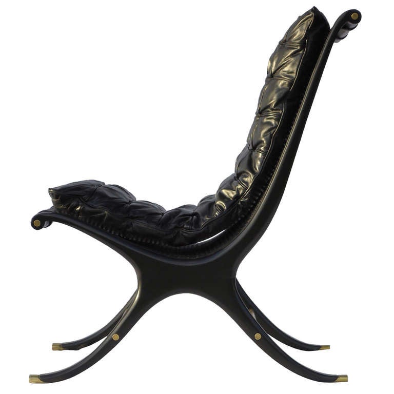 Gerald Jerome manufactured by Heritage a dramatic Mid-Century lounge chair designed in 1968. 

An unusual X-framed scoop chair having a sculpted black ebony frame with caning and brass stretcher bars and sabots. 

The original channeled black