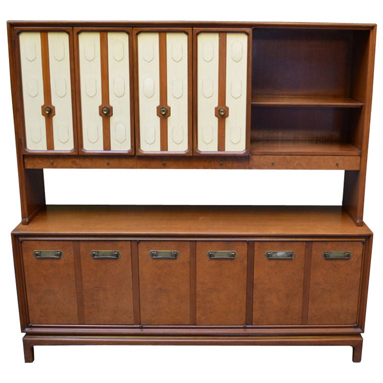 Credenza or buffet from the 1960s. Maple cabinet with bookmatched burl-wood faced doors across the base and two faux-ivory embossed accordion doors enclose 2/3 of the upper case. The upper case has a silver drawer and two shallow drawers for linens,