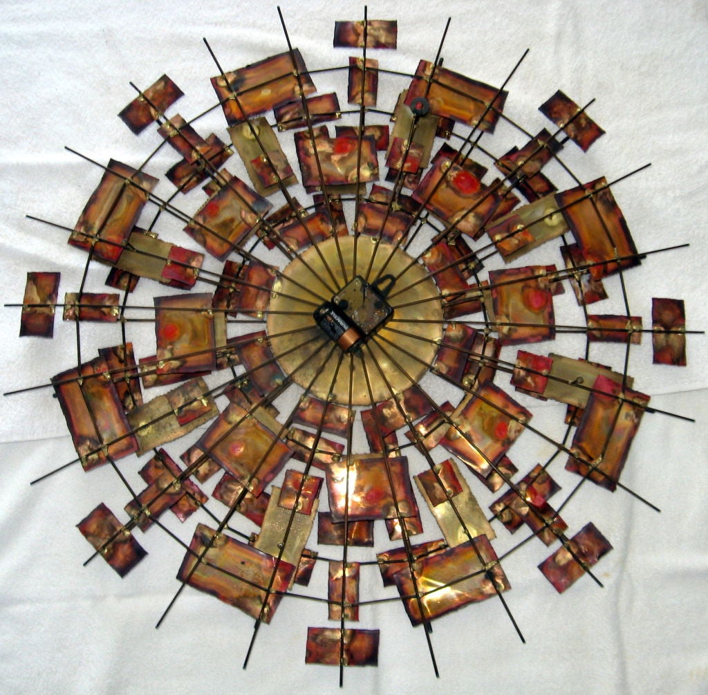 Striking multi-toned wall clock in the style of Curtis Jere Wall Clock. A three tiered construction of radiating brass rod provide the underlying support to multi-hued panels of rectangular and square brass. The clock mechanism is in good working