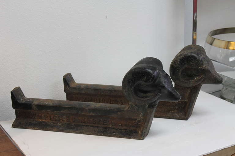 Ram’s head andirons signed Olympic Log Master  with patent information. Each andiron is 20” long, 8 1/2” high and 4 1/2” wide.