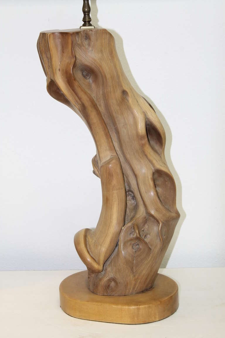 Driftwood table lamp. Polished hardwood with a satin finish. Wood element is 21 1/4” tall including the base. The base is approximately 9” by 7”. Original shade is 17 1/4” tall with an upper diameter of 20” and a lower diameter of 21”. Newly rewired.