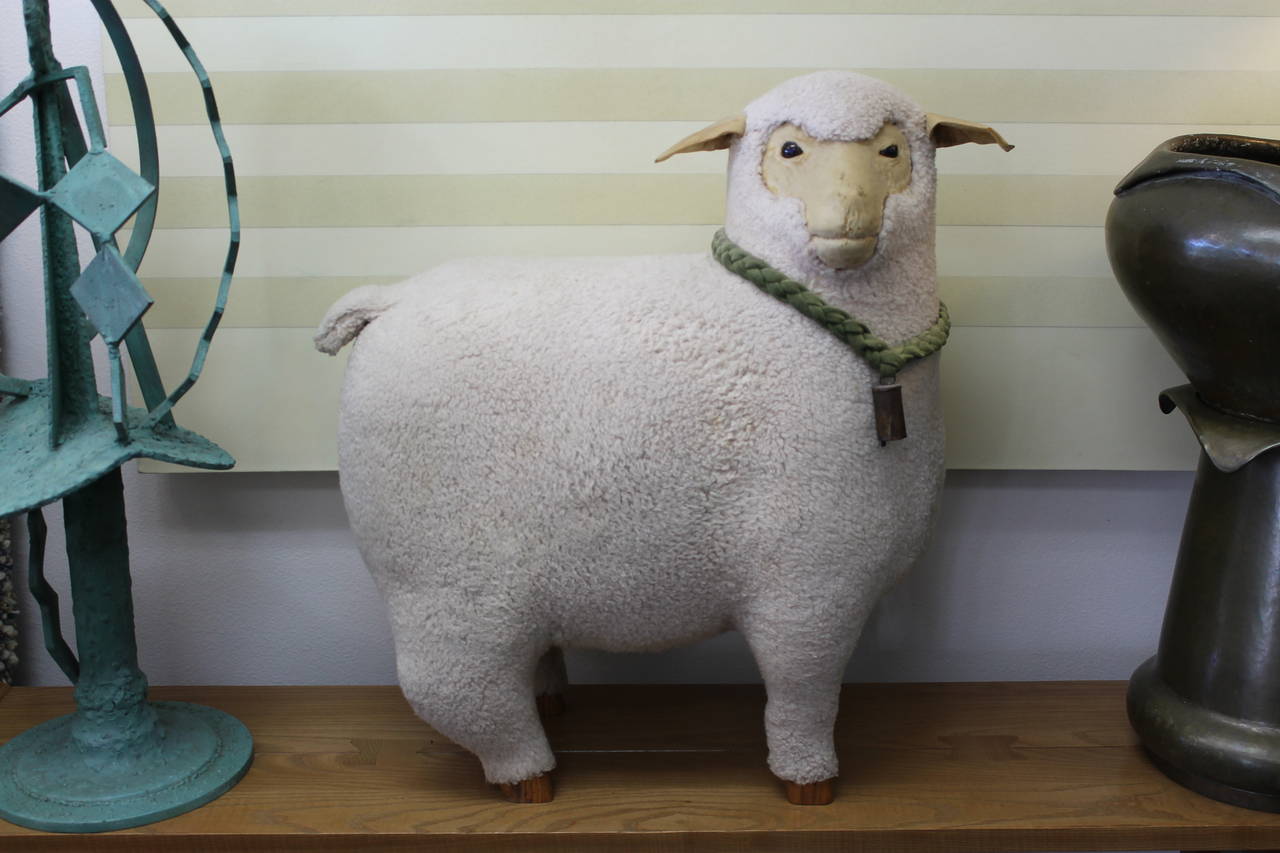 Carved wooden sheep covered in natural wool. The face is covered in what appears to be cotton velvet with some wear commensurate with age. Glass eyes. Beautifully hand signed on the inside of the hoof.  It's signed E. Arnold and dated 79.
