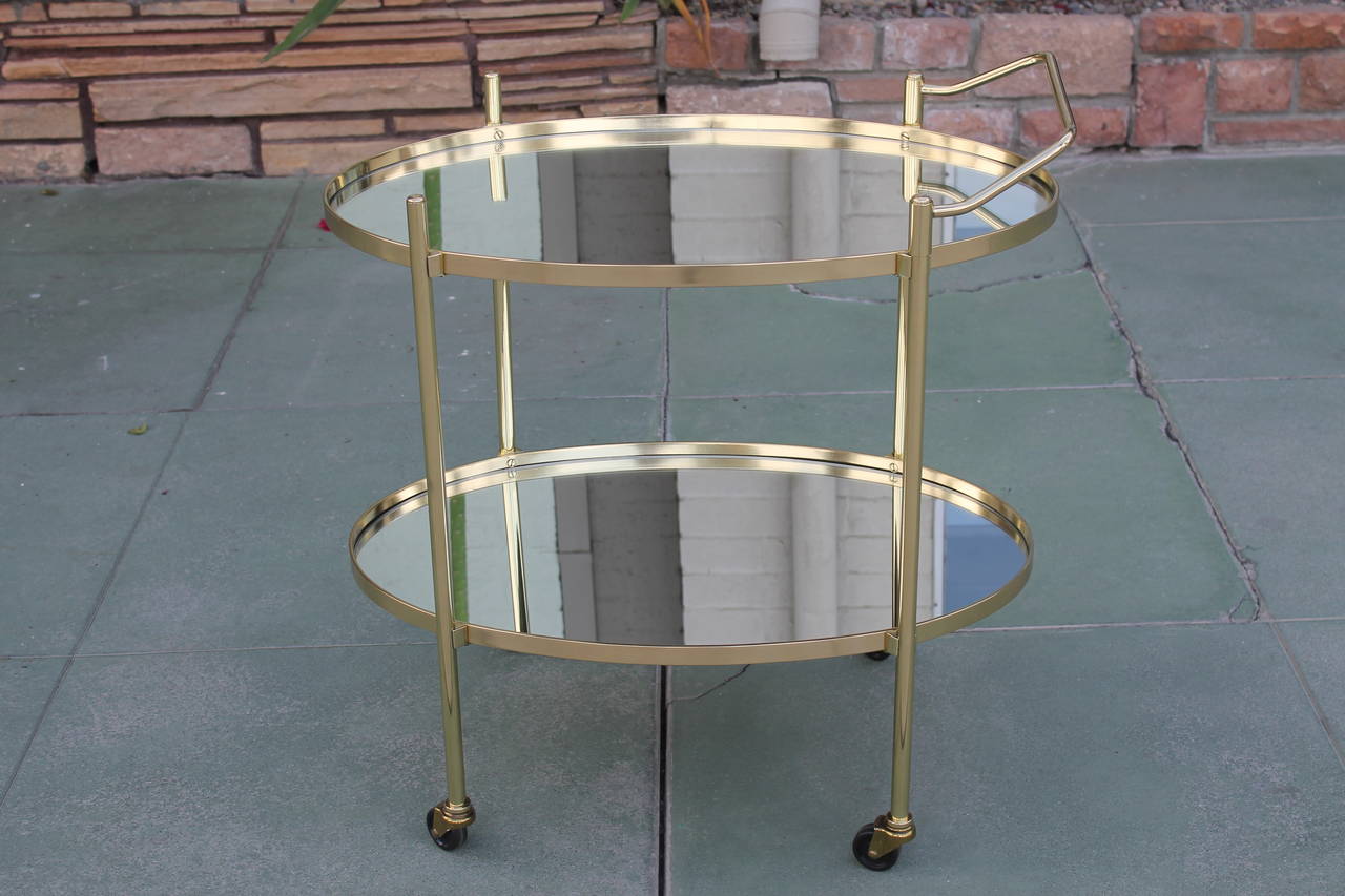 A high quality solid brass rolling bar cart by the Maxwell Philip Company, made circa 1960. All the brass has been professionally polished and sealed. New 1/4