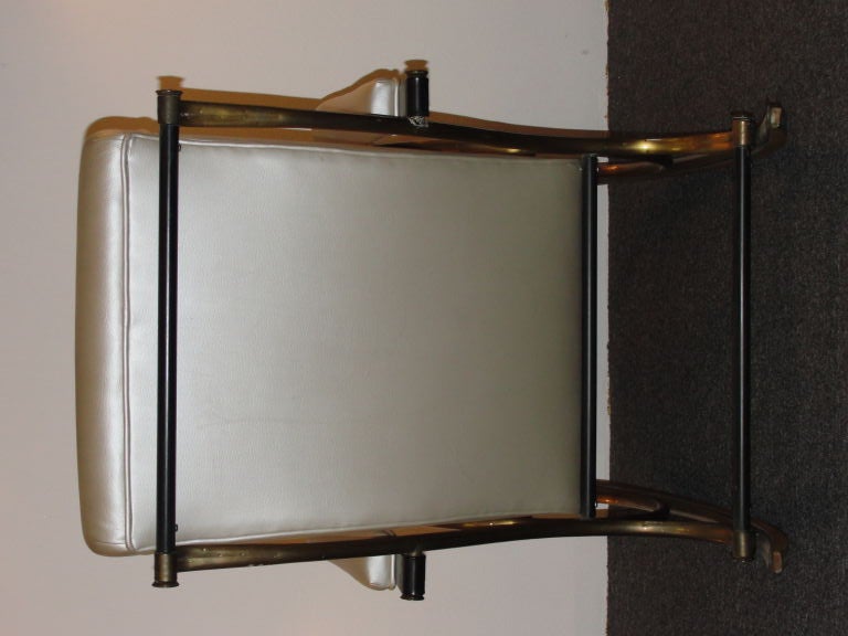 Lee Woodard & Sons armrocker chair.  Bent tubular brass-washed curvilinear tubular steel frame with random hammer marks, upholstered in tan vinyl.