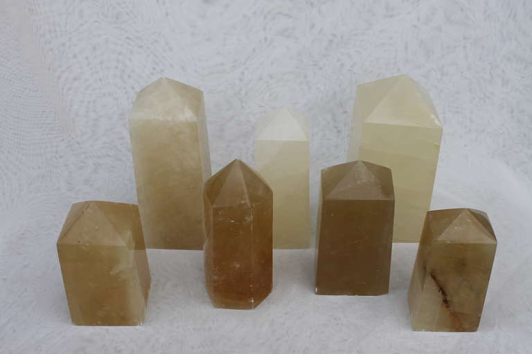 A collection of seven genuine natural Calcite crystal obelisk carvings, ranging from pale ivory to a soft honey color. These have lots of inclusions resulting in exciting light play. Sizes range from 6” in height to 9”.