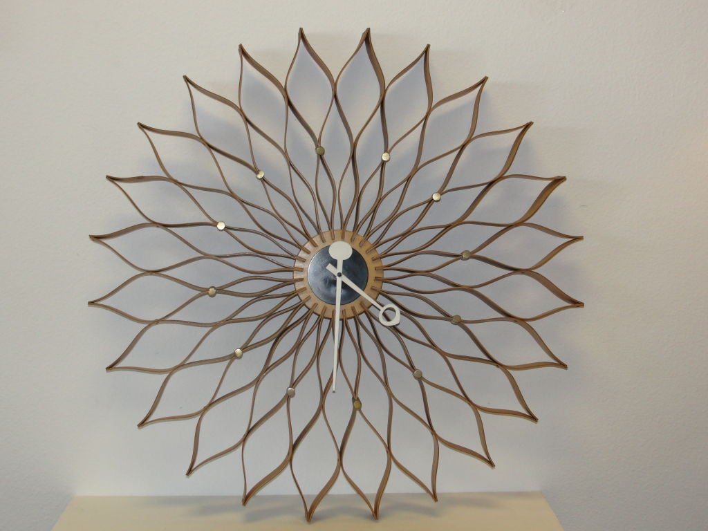 This is an original Sunflower clock designed by George Nelson for the Howard Miller Clocks company. Walnut & Birch plywood with black center, satin brass markers with white hands and wind movement. This is listed as model #2261 in the Howard Miller