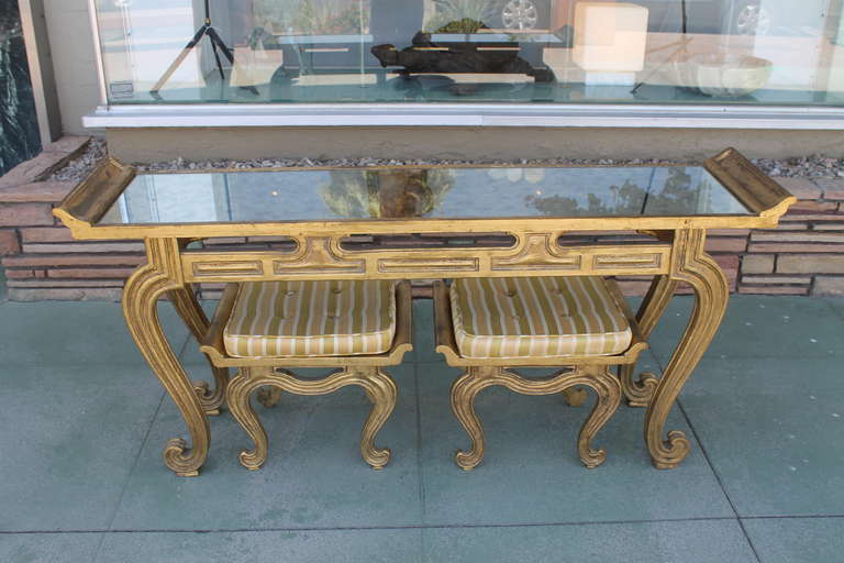 Vintage Francisco Hurtado Hollywood Regency console table and stools set. A gilt wood console table with matching seats by Spanish designer Francisco Hurtado. The table is inset with pale grey mottled mirror. The seats are complete with their