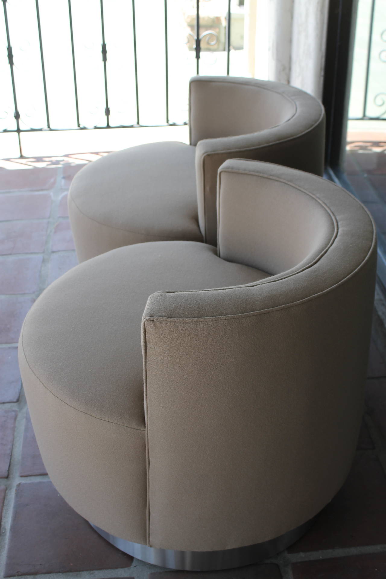 Pair of barrel chairs that swivel with chrome base.  In the style of Milo Baughman or Steve Chase.  Chairs have been professionally reupholstered with a wonderful beige / taupe fabric.  Chairs measure 28