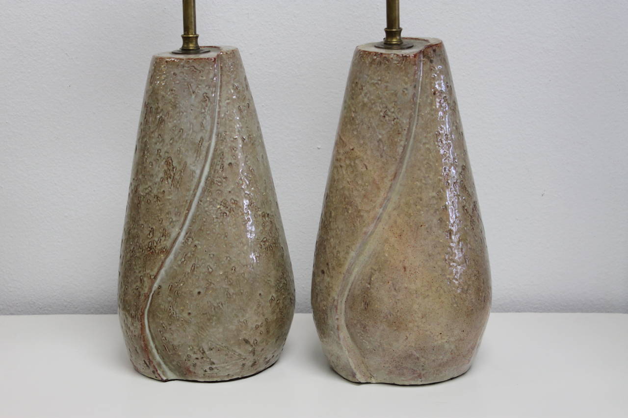 Pair of lamps by Eugene Deutch dated 1949.  Lamps have been professionally rewired. One of the lamps was cracked and has been repaired.  Ceramic portion is almost 13" high. Total height from base to the top of finial is 24.5".  
Eugene