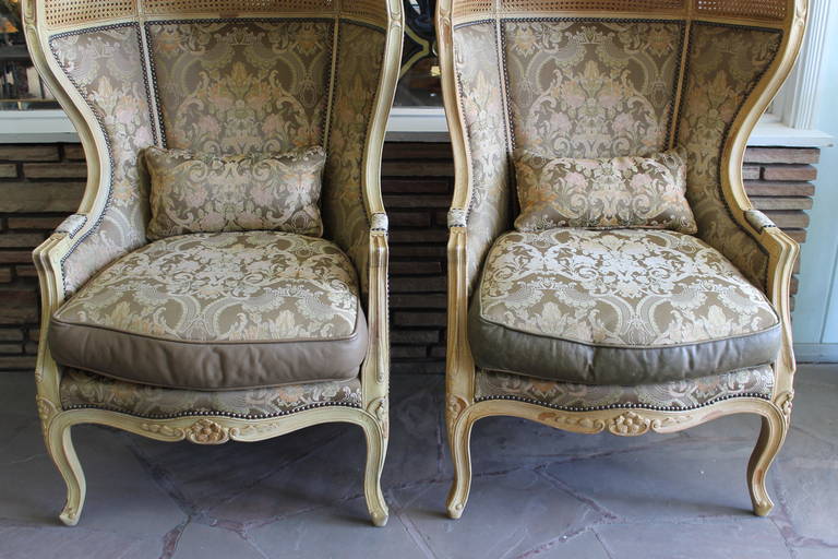 Two cab chairs from the Old Hickory Tannery Company upholstered in leather and brocade fabric with double-layered cane backs. Purchased in the 1950’s for a Monterey, California home. One seat cushion appears to have been recovered, as the leather is