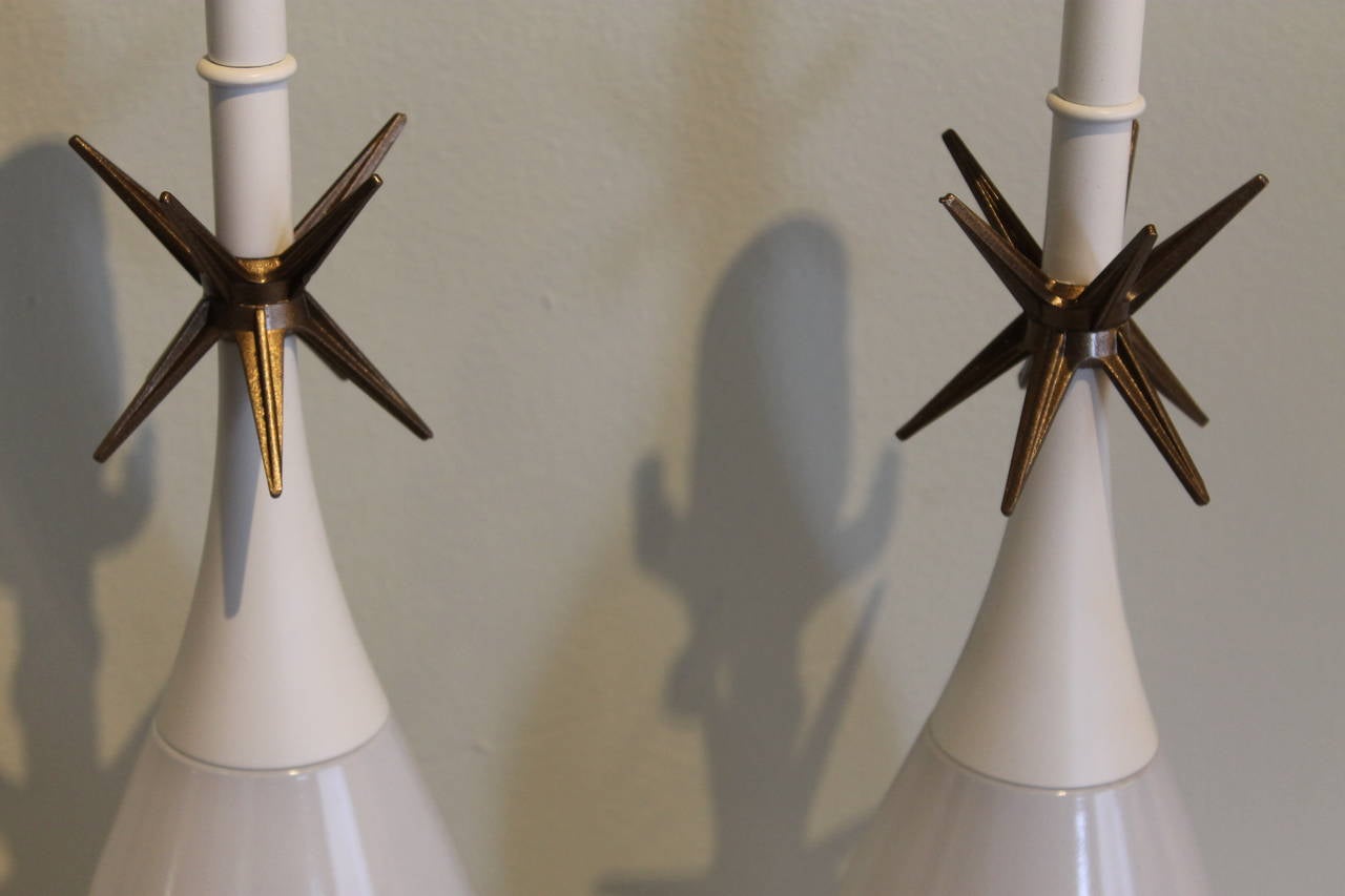 This pair of Mid-Century lamps features a Raymond Loewy designed bottle form with painted metal bases and Sputnik stars at the top. Loewy designed a series of holiday season liquor bottles for Old Forester in the 1950s, this design being among them.