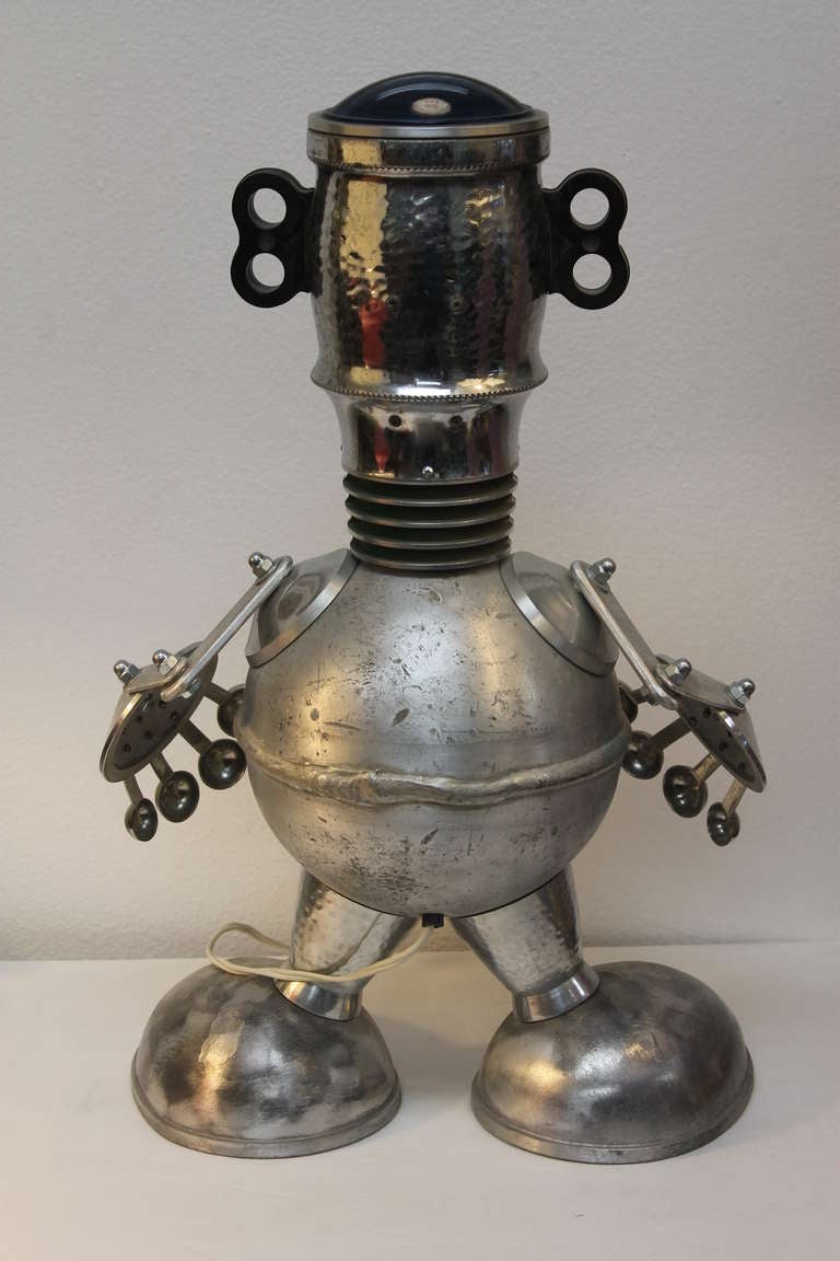 Whimsical aluminum robot lamp by northern California artist Jim Bauer.  Jim uses found aluminum items to create figural sculptures.  The eyes and glass portion on his head lights up.