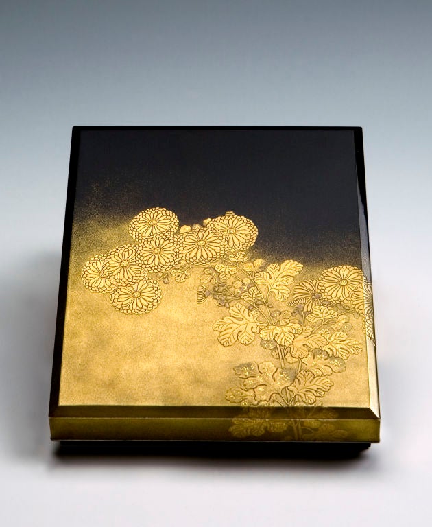 The cover of the box is decorated with two groups of chrysanthemums with numerous flowers and buds, presented in takamakie high-relief gold lacquer in two tones. The leaves and the center of the flowers are adorned with many inlaid squares of