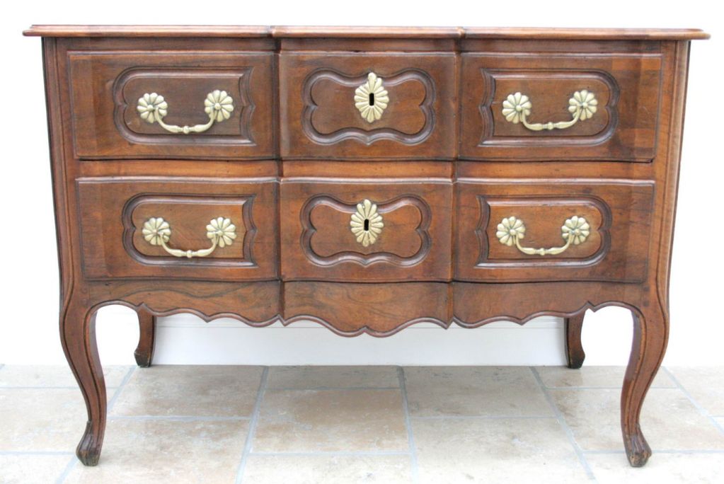 An Eighteenth Century French Walnut chest en arbalete, the two drawers with moulded cartouches and replacement scalloped brass hardware, standing on elegant tapering cabriole legs.