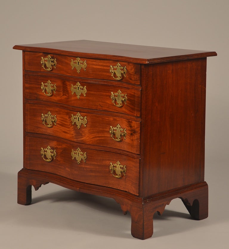 Superb tiny Boston Chippendale mahogany blocked serpentine chest of drawers with bold graduation (the top drawer is almost half the size of the bottom drawer).   
The cockbeaded case has blocked ends that continue down through the conforming