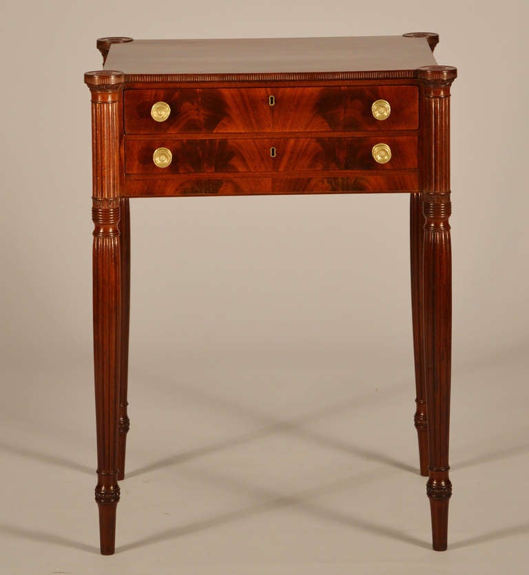 A superb Salem Sheraton mahogany carved two drawer work table with the work bag sliding to the side. It has carved cookie corners on the top over conforming three-quarter applied turned and reeded legs .   The amazing legs feature carving (from the