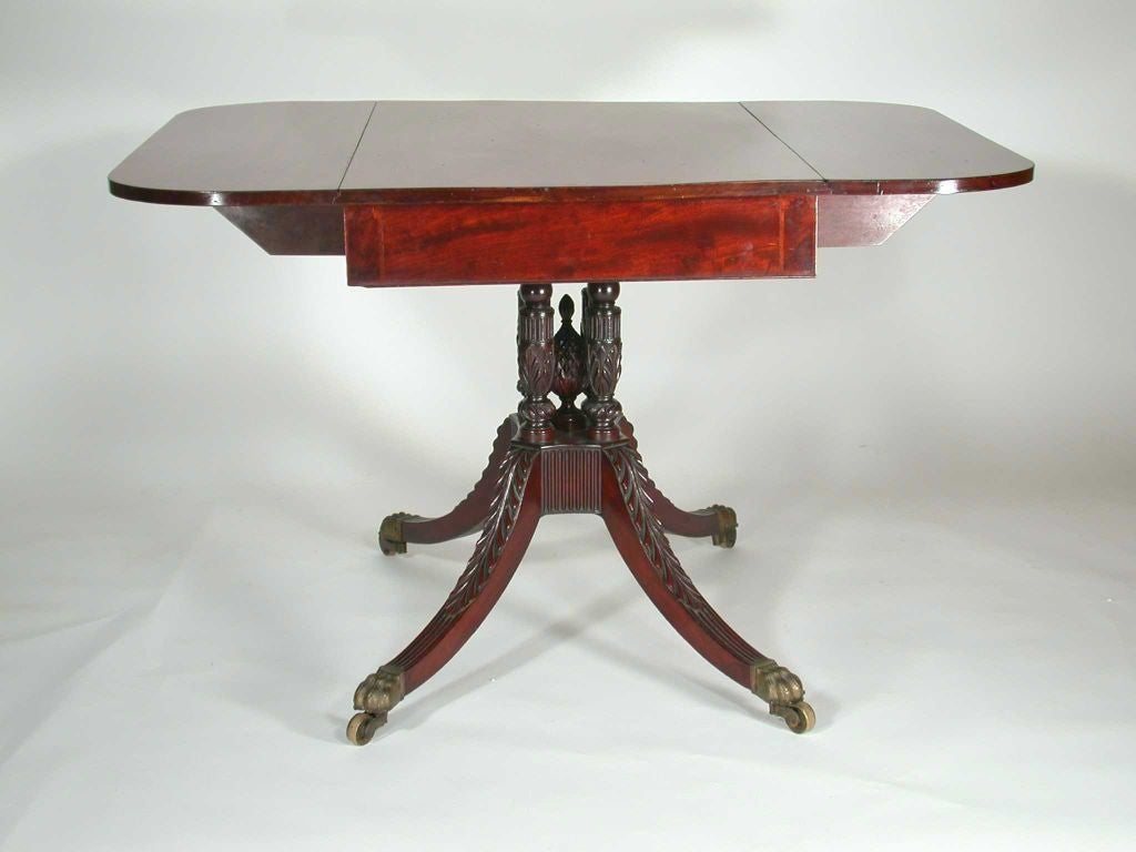 New York mahogany drop leaf breakfast table by Duncan Phyfe or cabinetmaker of equal stature. Beautiful solid mahogany top over  turned and carved base with pineapple final and hairy paw brass castors. <br />
<br />
The base is identical to ones