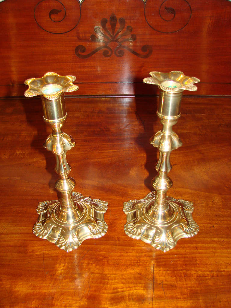 Superb matched pair of English six-lobbed petal-base brass candlesticks with shell decoration and matching removable bobeches.

Note the lobed definition on the center knops.

Reference:  The Brass Book by Herbert Schiffer (page 201)
“These