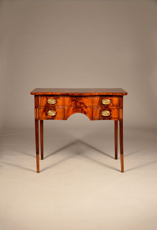 A delightful English Sheraton mahogany dressing table. This table has a nicely shaped serpentine base with conforming top. The front and top are thoughtfully veneered with bold 