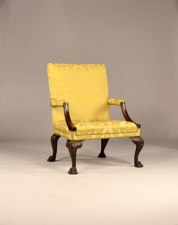 A striking George ll carved mahogany library chair with shell and pendant leaf-carved cabriole legs. The legs end in four bold, hairy lion's paw feet with carving all the way around.  The curved arm supports are decorated with three carved panels.