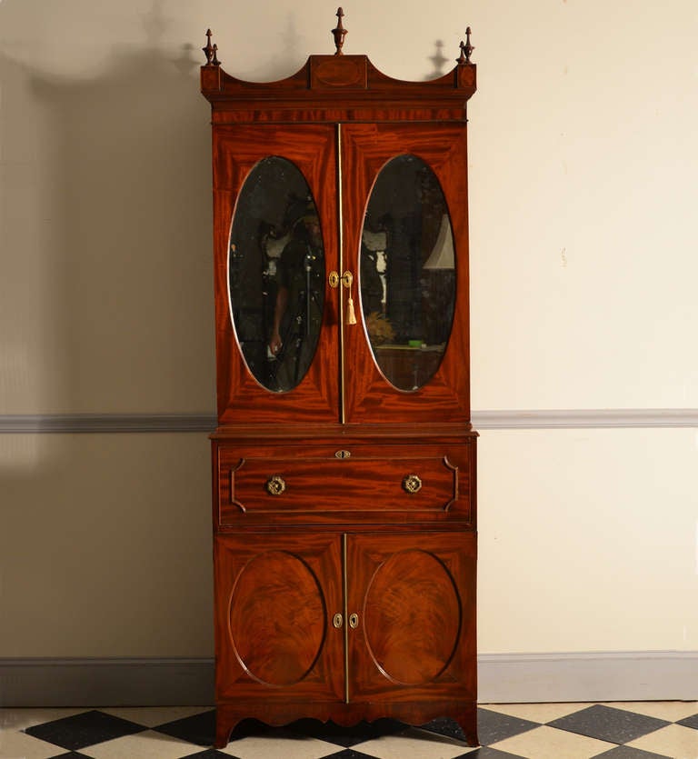 Very small George III mahogany secretary with oval mirrors in the top section and oval panels in the base.
The fold down butler's desk has a fitted interior with cubby holes and drawers with original ivory knobs.

Wonderful form!

