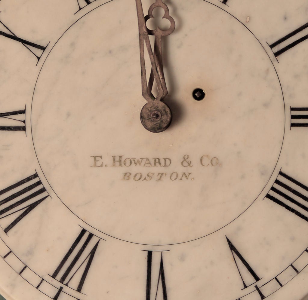 A graceful white marble wall clock made by E. Howard & Co. Boston. The well proportioned clock face is made of one piece of marble fastened to the pine case with two screws at the 3 'clock and 9 o'clock positions. Roman hours and Arabic numbers are