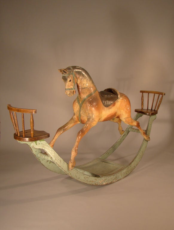A wonderful rocking horse with a small child's oak spindle back chair at both ends of the pale blue rockers. The horse sports a padded and paint embellished saddle with a green bridle, harness and wonderful glass eyes. Great old surface.