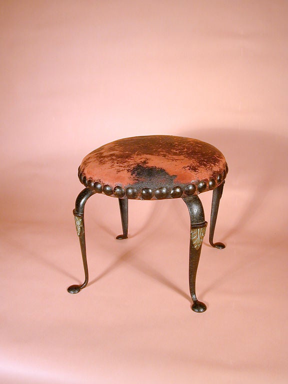 Superb cabriole leg iron stool with leather covering and brass studs.  Note the original brass leaves that decorate the legs.
