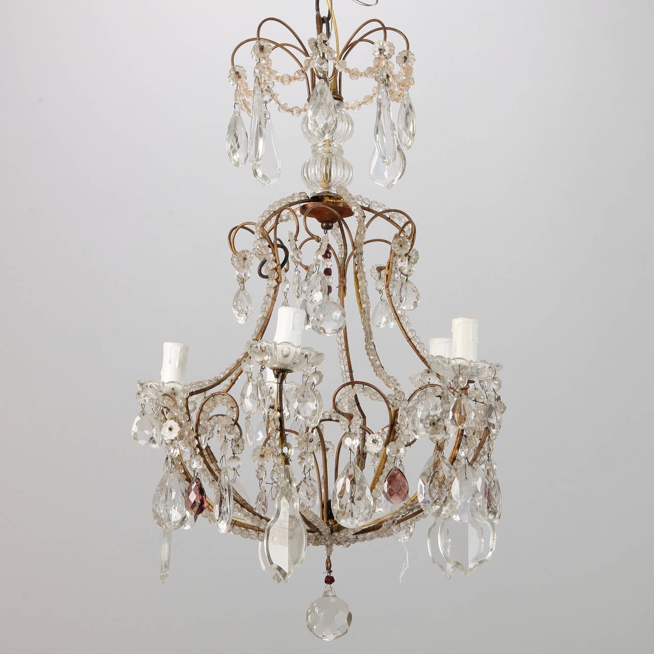 Circa 1920s French chandelier has a brass, cage-shaped frame with five candle style lights, three tiers of clear, faceted crystal pendants with amethyst accents and beaded arms. New electrical wiring for US standards.