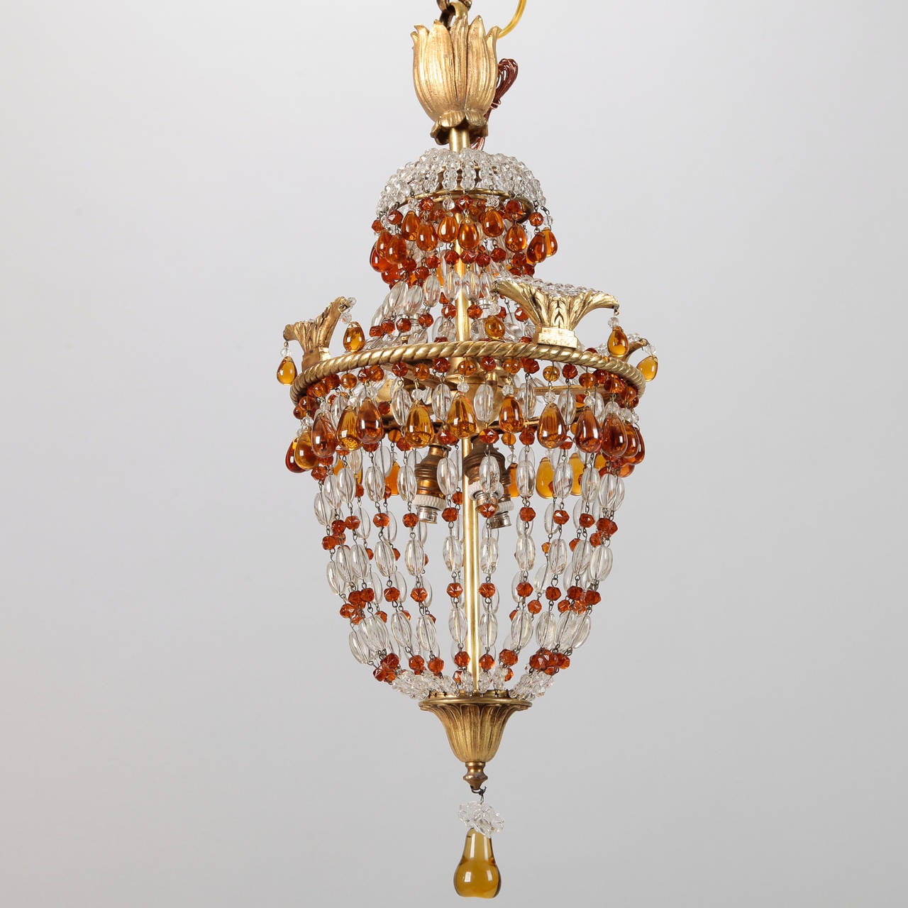 Circa 1890s small French chandelier with twisted form bronze frame supporting clear and amber crystal beads in basket shape. Internal light sockets, tulip form top ornament and pear shaped glass center drop. New wiring for US electrical