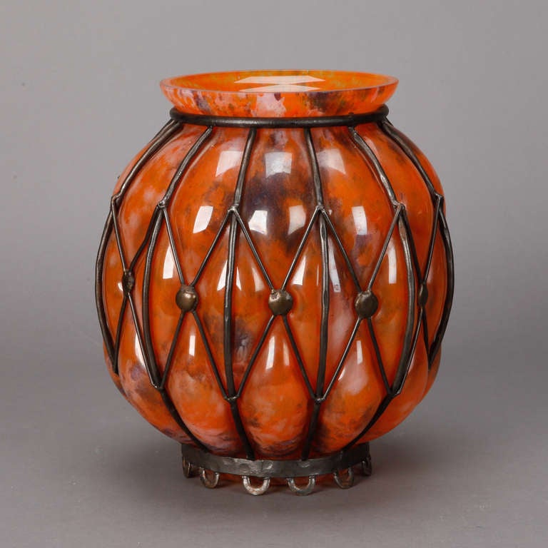 Circa 1940s orange pate de verre globe form vase with a black metal surround in an open work diamond pattern.