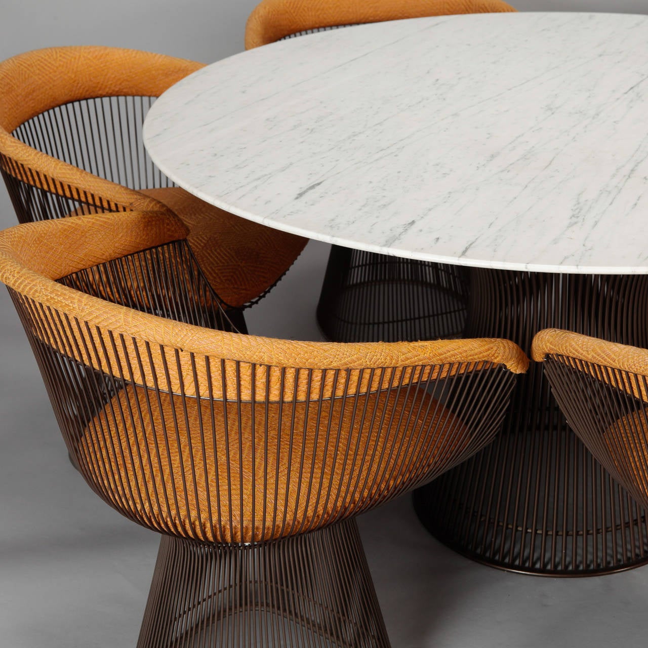 Circa 1960s Knoll dining table with six chairs set designed by Warren Platner.  54” diameter table has beveled edge Italian carrarra marble top and bronze finish metal base. Six coordinating chairs with bronze finish and original gold jacquard
