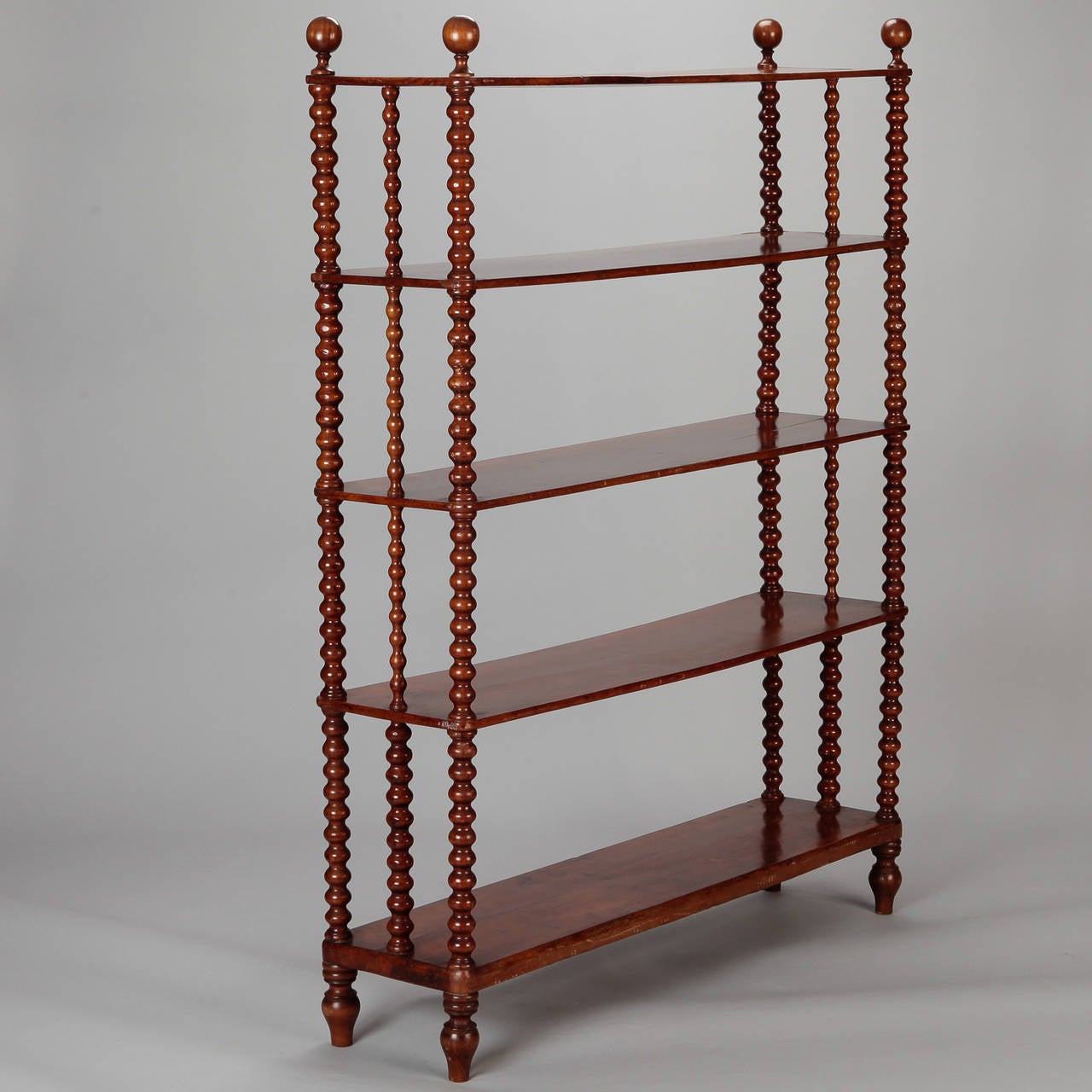 Circa 1900 Italian walnut etagere with five fixed shelves, triple side supports with turned bobbin design topped with round wood finials.