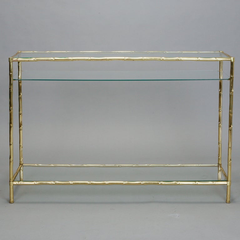 Circa 1950s Italian console table has a faux bamboo brass frame with glass table top and two lower shelves. 