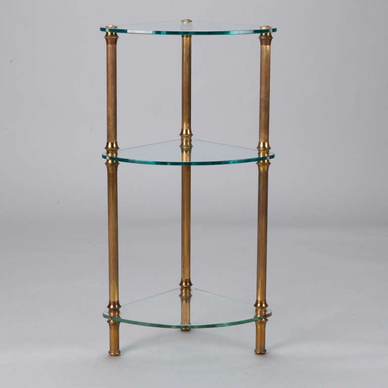 Circa 1940s three tier French corner etagere with reeded brass supports and thick glass shelves.