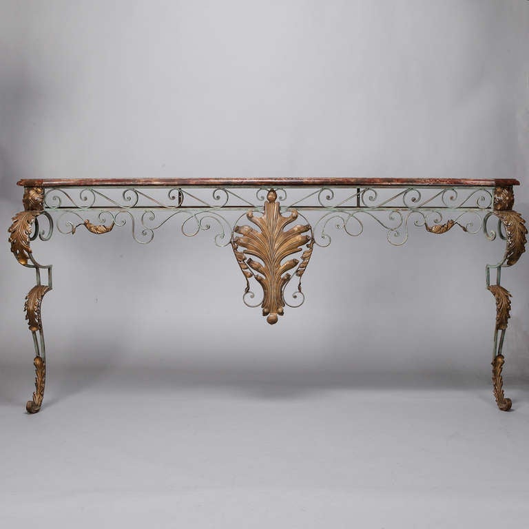 Long and narrow wall mounted French console with a painted and gilded iron base and faux marble top. Iron base has painted green finish, large gilded ornamental element and cabriole legs with applied leaf-form gilded tole pieces. Depth shown is