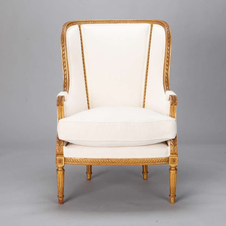 Circa 1860 Louis XVI style wing back bergere with carved and gilded wood frame, down-filled seat cushion and newly upholstered in muslin - ready for the fabric of your choice. Seat is 22” high and 21” deep, arms are 25” high.  Seat Depth:  21
