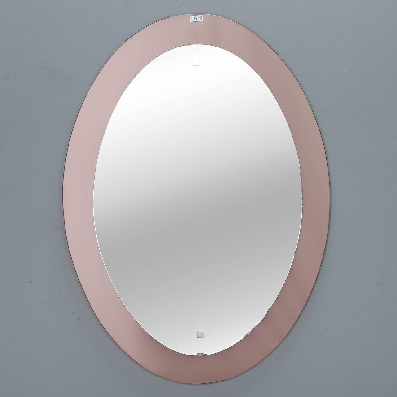 Circa 1970s Mid Century Italian oval mirror attributed to Cristal Art with floating frame of pale apricot colored glass.