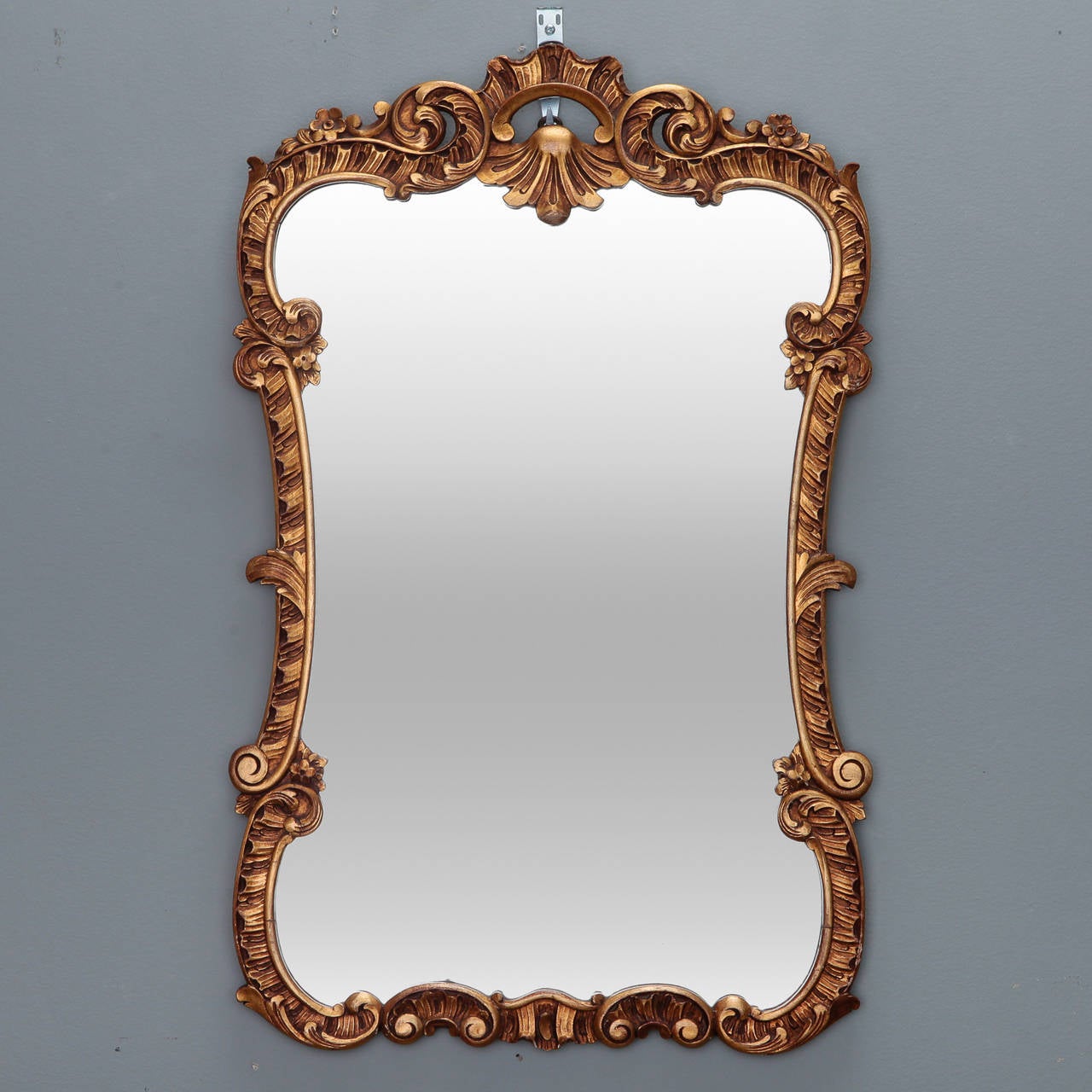 Circa 1930s Italian gilt wood frame mirror with fancy scrolled frame with floral and foliate details and shell form crest.