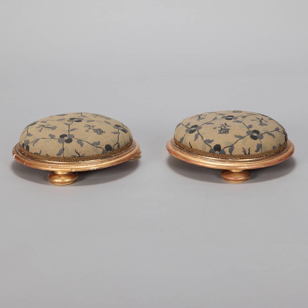 Pair of circa 1880s small low, footstools with round, gilt wood frames, bun feet and needlepoint upholstered cushions. Found in France. Sold and priced as a pair.