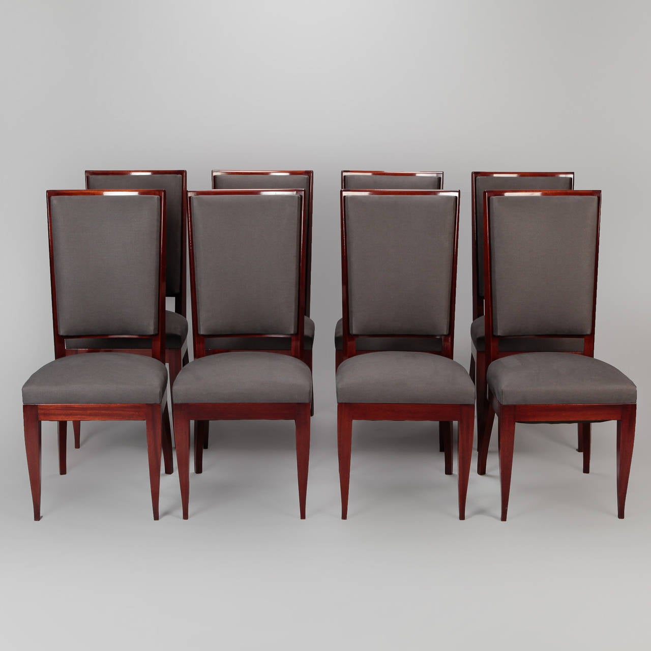 Circa 1930s set of eight tall back, armless French Art Deco dining chairs. Polished hardwood frames with graceful, tapered legs. Seats and backs newly upholstered in gray fabric. Seats are 18.5” high and 16.25” deep. Sold and priced as a set.