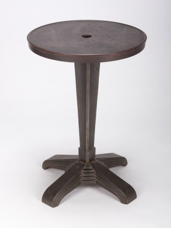 This small Art Deco iron industrial table has a round table top and stepped-style pedestal base.