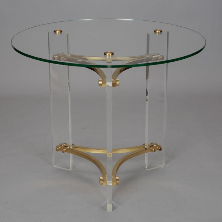 Circa 1960s side table by the American designer known for his innovative work with Lucite. Tripod base of Lucite panels with solid brass supports and a round glass table top.