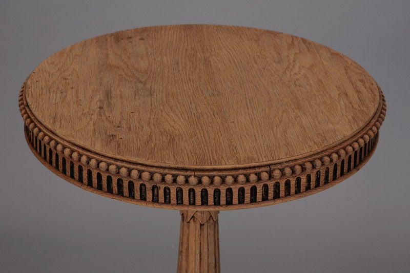 Turn of the century small Louis Philippe style bleached oak pedestal / gueridon table. Table top is 18.25” diameter and has beaded and fluted edge. Leg has carved foliate and fluted detail and base has four highly carved feet. Great piece in a