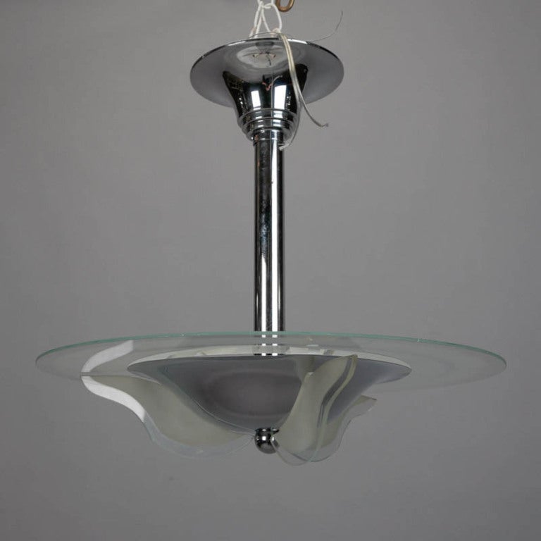 Modernist light fixture has a chrome ceiling canopy with stepped details, a chrome shaft and a clear glass disk embellished with contrasting satin and polished glass disks and ribs. Three internal candelabra size sockets. New wiring for US