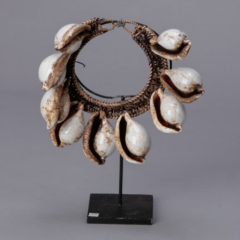 Circa 1920s traditional African necklace of large cowry shells and woven reeds mounted on an iron stand.