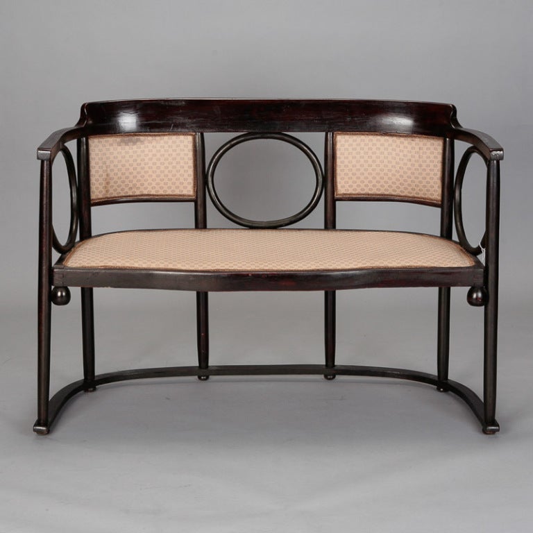 Circa 1906 dark stained walnut bench designed by Josef Hoffmann has a curved seat back with openwork bent wood circles and upholstered panels. Curved base and upholstered seat that is 17.5” high. Great example of Hoffmann’s most iconic work. We have