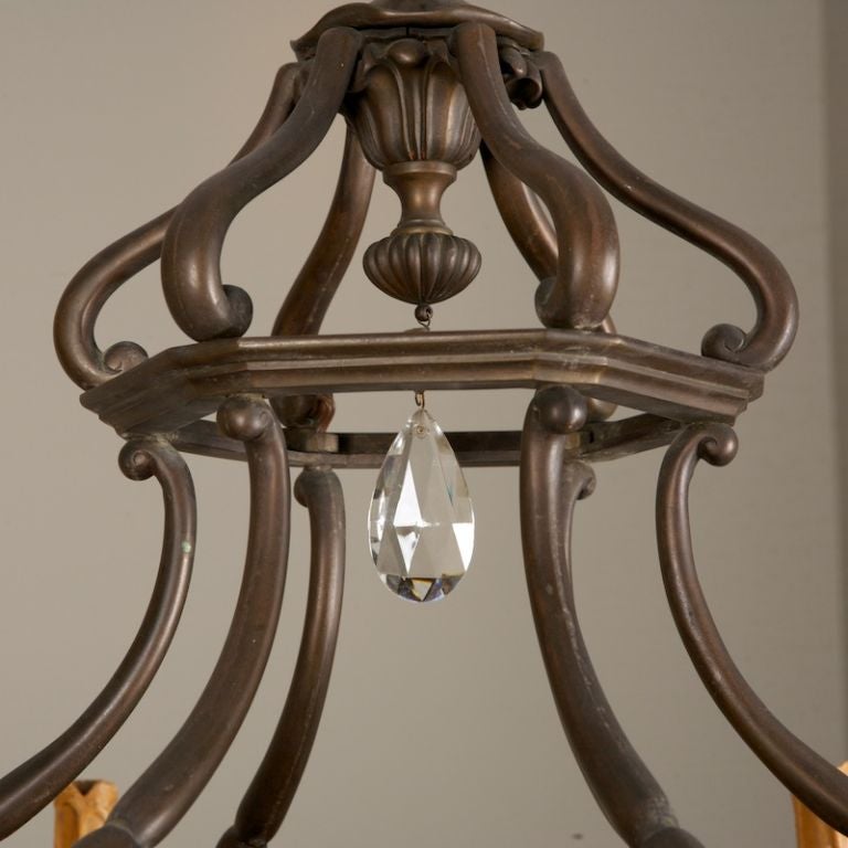 This circa 1890 fixture has an open work bronze frame, amber glass center insert, 6 candle style lights and large clear crystal drops.
# of Sockets:  9 (6 arms & 3 center)
Socket Type:  6 Candelabra & 3 Regular