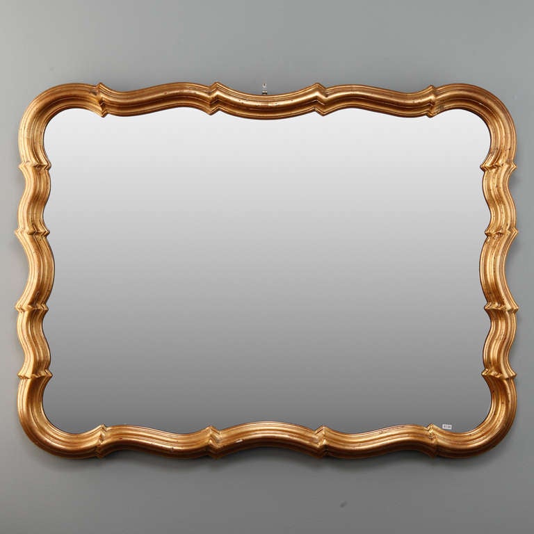 Circa 1930s French mirror with a scalloped edge wood frame with gold leaf finish. Mirror can be hung horizontally or vertically.