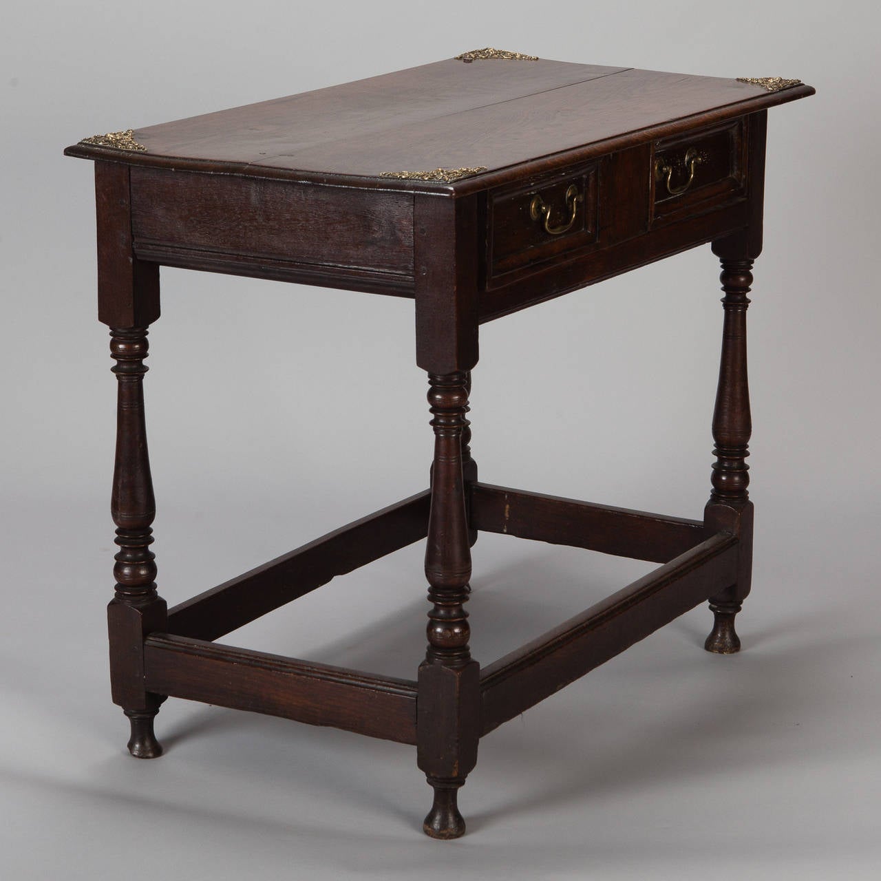 Circa 1830s dark oak side table from Portugal has two drawers, original brass fittings and decorative turned legs.